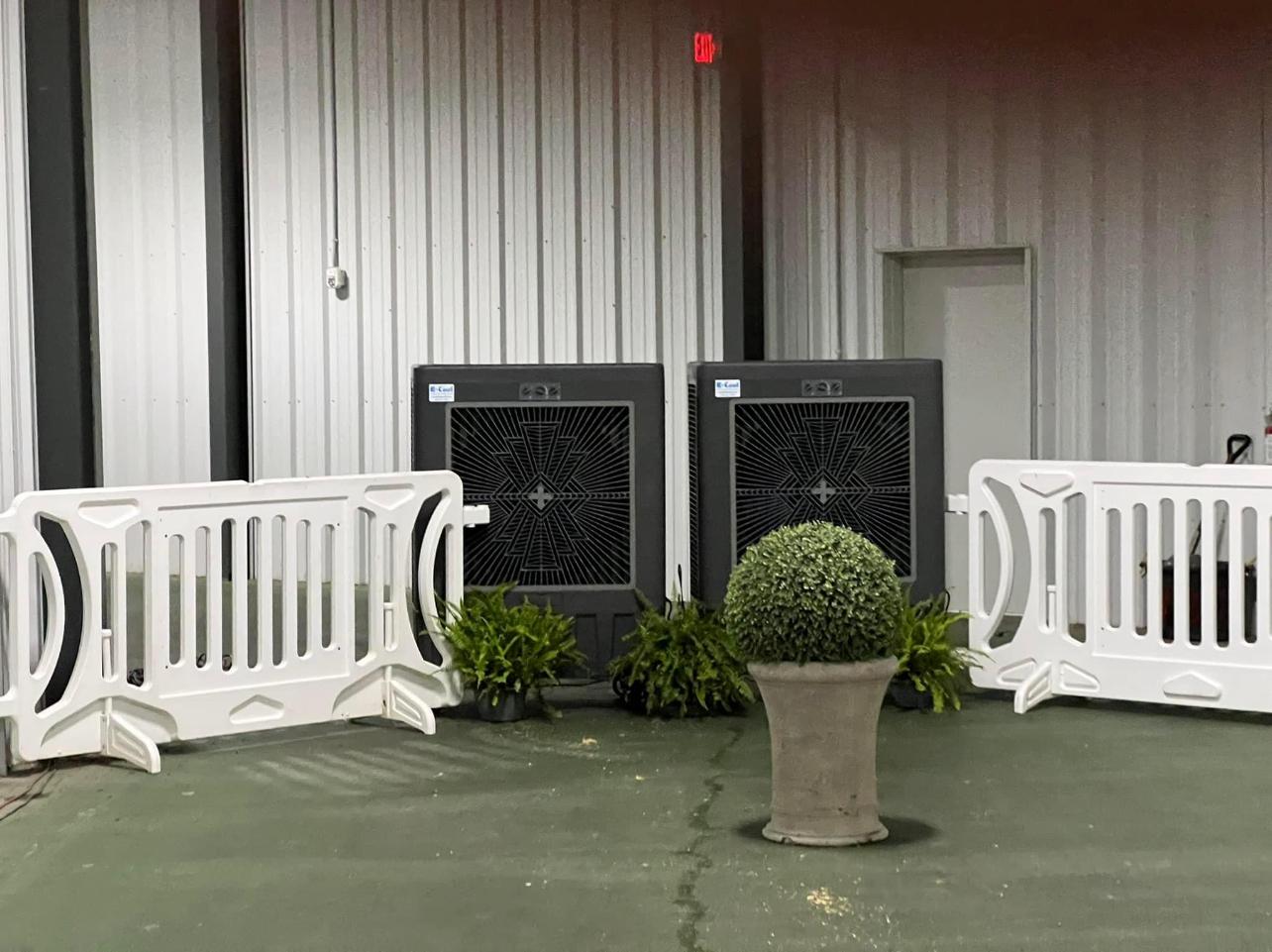 Two portable coolers behind white barriers and potted plant.