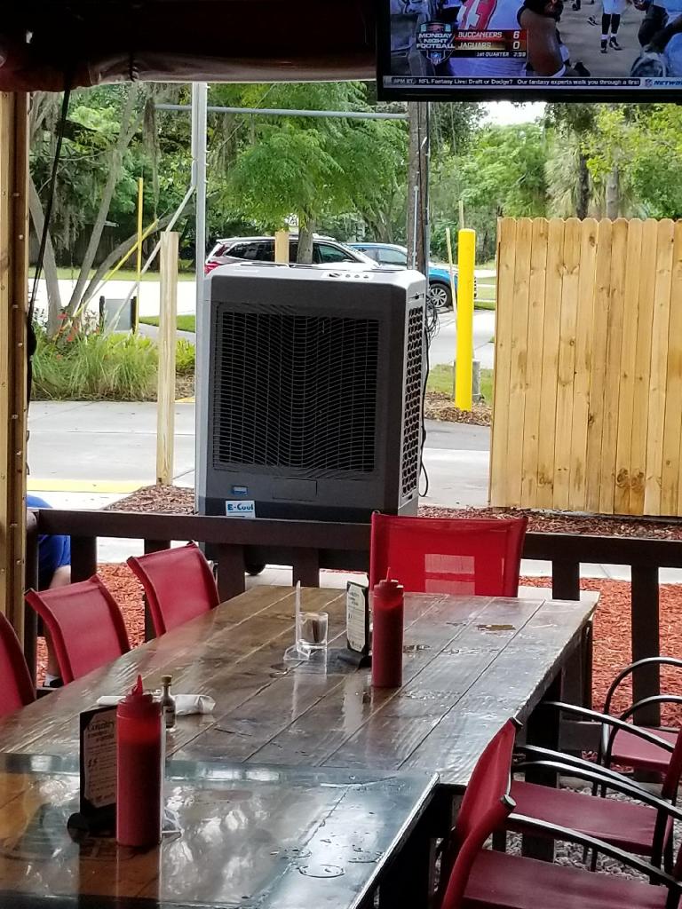 m61 on stand Outdoor dining area with red chairs and air cooler.