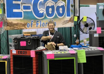 Man at cooling equipment booth with fans and boxes.