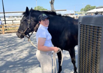 Smiling woman with black horse outdoors.