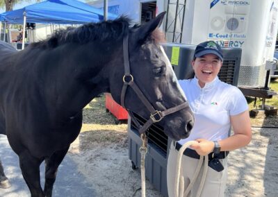 Smiling person holding a black horse's reins.